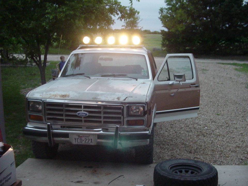 Ford Bronco with roof lights and open door, parked outside