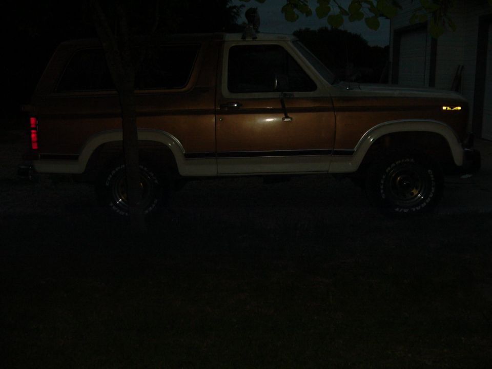 Brown and white Ford Bronco parked at night, side view