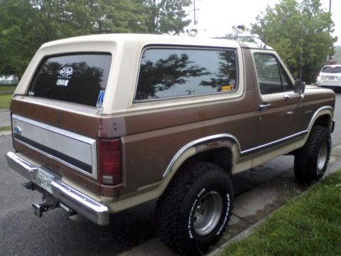 1986 Ford Bronco - Rear view of a 1986 Ford Bronco with aftermarket tires and a two-tone paint job.
