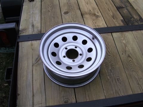 2005 Ford F-250 - A single steel wheel is placed on a wooden trailer. The wheel has a silver finish and multiple circular cutouts.