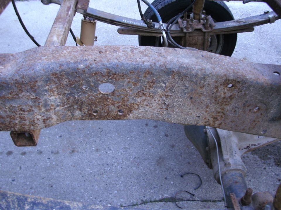 Rusted truck frame section with leaf springs and shock absorber visible