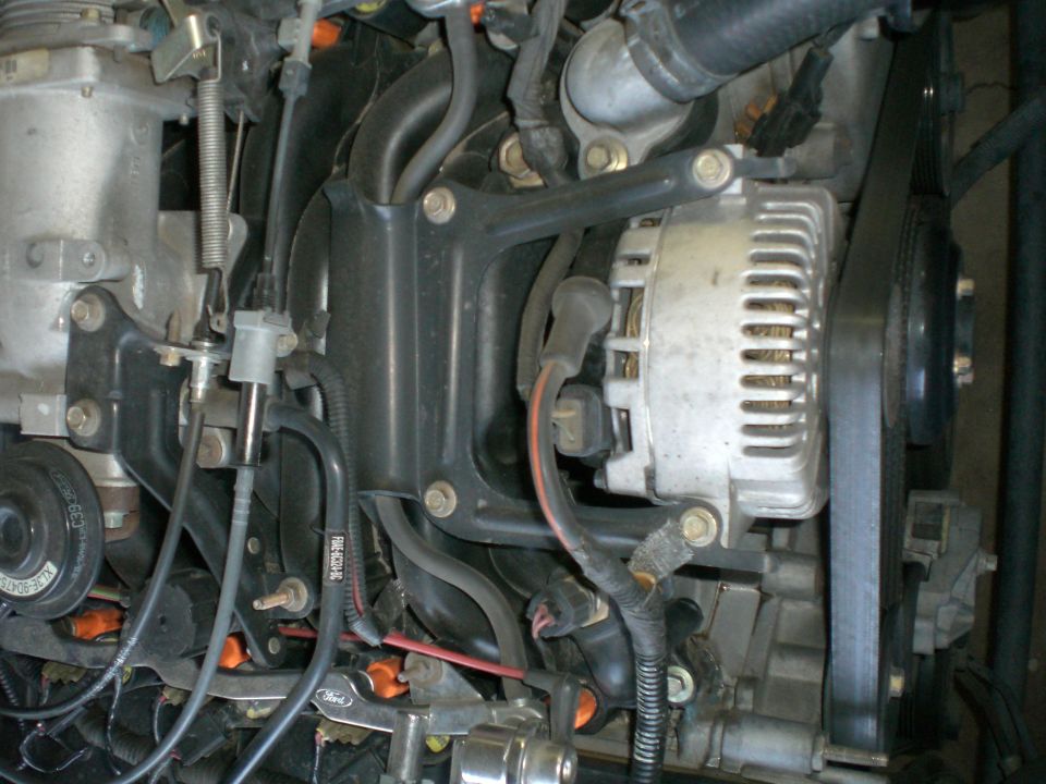 Engine bay shot showing alternator, belts, and various hoses and wires
