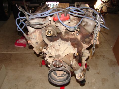 1996 Ford Bronco - Engine assembly on a stand, showing various hoses, wires, and a chain for lifting.