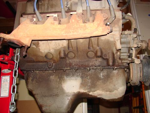1996 Ford Bronco - Engine block and exhaust manifold, likely needing repair due to oil leaks.