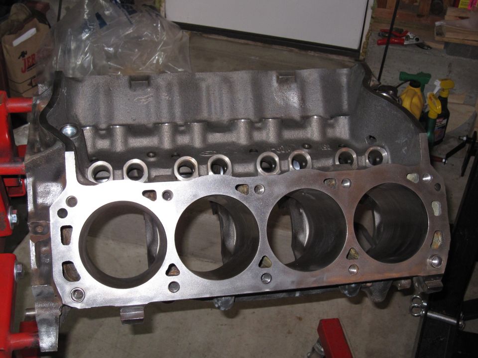 Bare four-cylinder engine block deck showing cylinder bores