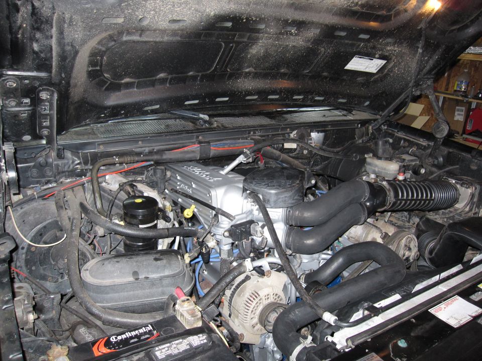 1996 Ford Bronco engine bay with a supercharger installed. Silver valve covers are visible
