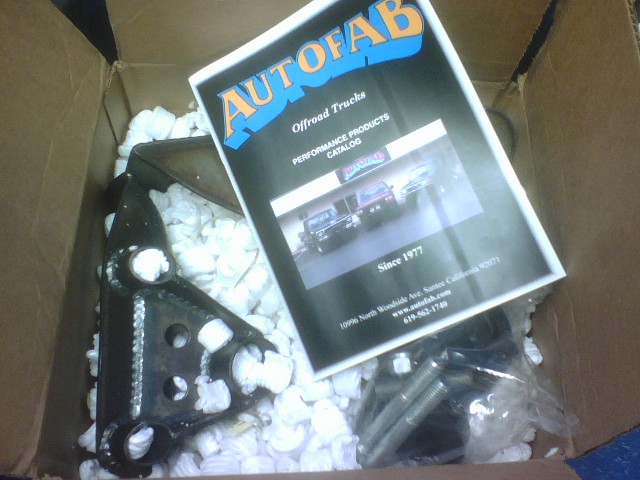 Cardboard box with AutoFab catalog and a metal part. Catalog shows three trucks