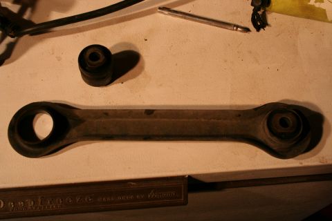 2001 Subaru Legacy - Close-up of a car's suspension control arm and a separate bushing, likely for replacement.