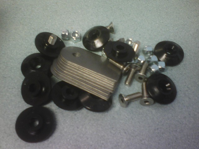Stack of stainless mounting tabs with black cushion washers, bolts and nuts on a counter