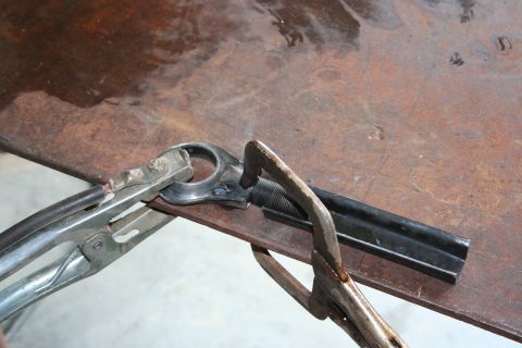 2001 Subaru Legacy - Welding clamps are used to secure a metal component for repair or fabrication on a workbench.