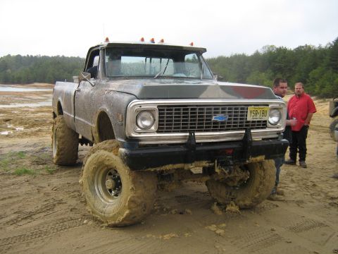1990 Ford Bronco - This heavily modified Chevrolet pickup truck is covered in mud, its large off-road tires and a custom front bumper.