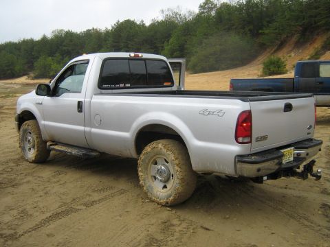 1990 Ford Bronco - Silver Ford F-250 pickup truck seen off-road with another truck in the background.