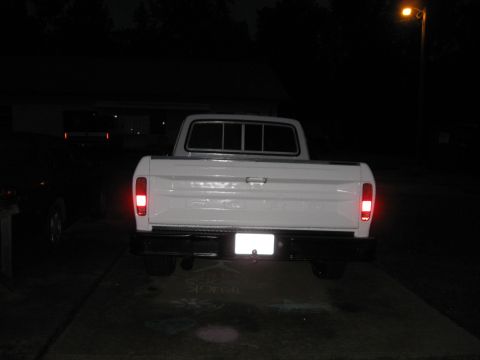 1995 Ford Bronco - A white pickup truck is viewed from the rear at night, parked on a driveway.