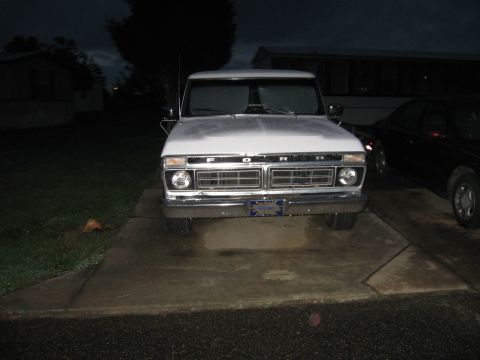 1995 Ford Bronco - The front of a white Ford F-Series truck is visible, parked in a driveway under a dark sky.