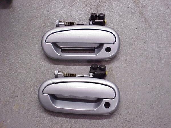 Two silver car door handles with black mounting hardware and springs