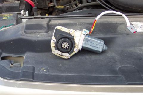 2007 Ford Mustang - A window motor assembly is shown removed from its vehicle, lying on the engine bay cover.