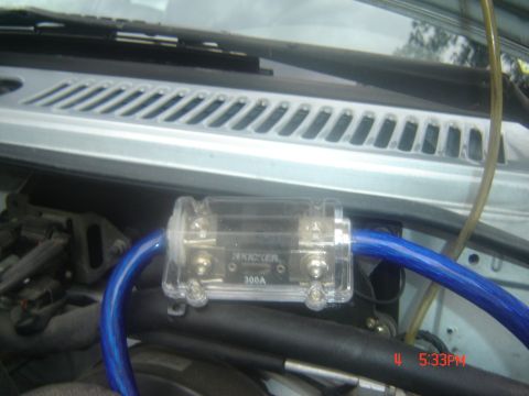 1995 Ford Aspire - Close-up of an inline fuse holder with a blue wire and visible 'KICKER 300A' text, likely part of a car's audio system.