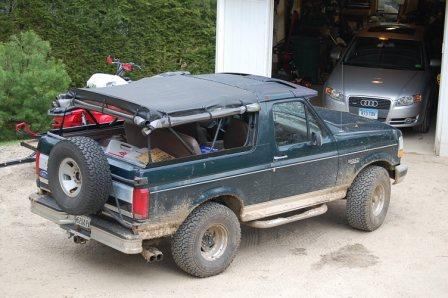 1993 Ford Bronco - Green 1993 Ford Bronco with a soft top removed, parked next to an open garage containing a silver Audi.