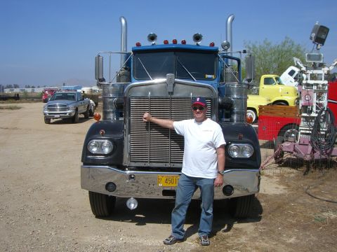 1981 Kenworth W900A - A man poses in front of a classic Kenworth W900A truck at an outdoor event.