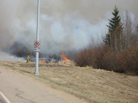 1996 Dodge 2500 - A firefighter battles a grass fire, with thick smoke billowing into the sky. A signpost stands nearby.