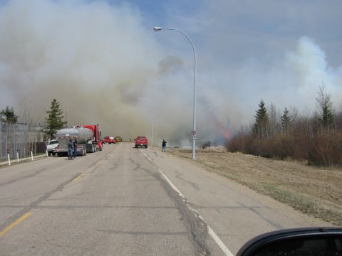 1996 Dodge 2500 - Emergency vehicles are on scene responding to a wildfire that is burning near a wooded area.