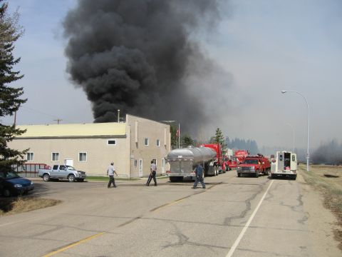 1996 Dodge 2500 - Emergency vehicles are on the scene of a fire, with thick black smoke billowing into the sky.