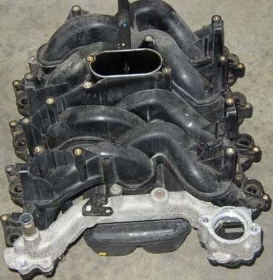 2007 Ford Mustang - A black plastic intake manifold with silver metal mounting flange is shown from a top-down angle.