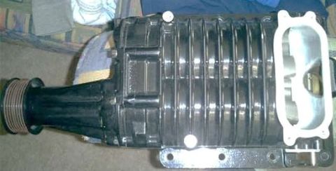 2007 Ford Mustang - A black supercharger, likely for an engine, is shown with its ribbed housing and intake manifold opening visible.