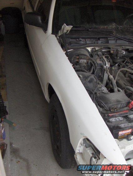 2003 Ford Crown Victoria - Front fender and engine bay of a 2003 Ford Crown Victoria. Hood is open, showing engine components.