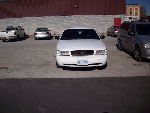 2003 Ford Crown Victoria - Front view of a white 2003 Ford Crown Victoria parked in a lot, showing its grille and license plate.