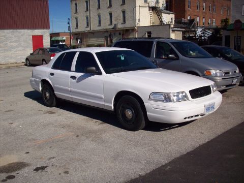 2003 Ford Crown Victoria - White 2003 Ford Crown Victoria parked in a lot, with a silver minivan visible behind it.