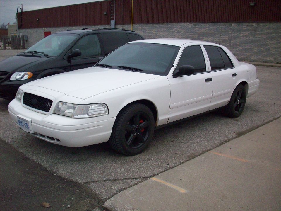 2003 Ford Crown Victoria parked next to a black minivan