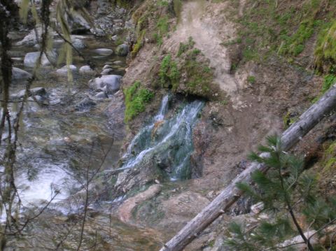 1996 Ford Bronco - A natural waterfall flows over mineral-stained rocks beside a rocky stream bed.