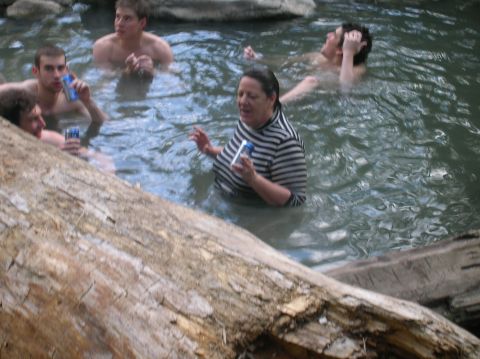 1996 Ford Bronco - Several people relax in a natural hot spring, partially obscured by a large log in the foreground.