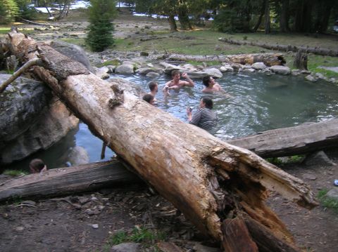 1996 Ford Bronco - A group of people enjoy a soak in a natural hot spring surrounded by rocks and trees.
