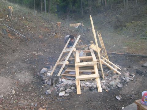 1996 Ford Bronco - A person is constructing a wooden frame structure outdoors on a dirt slope with trees in the background.