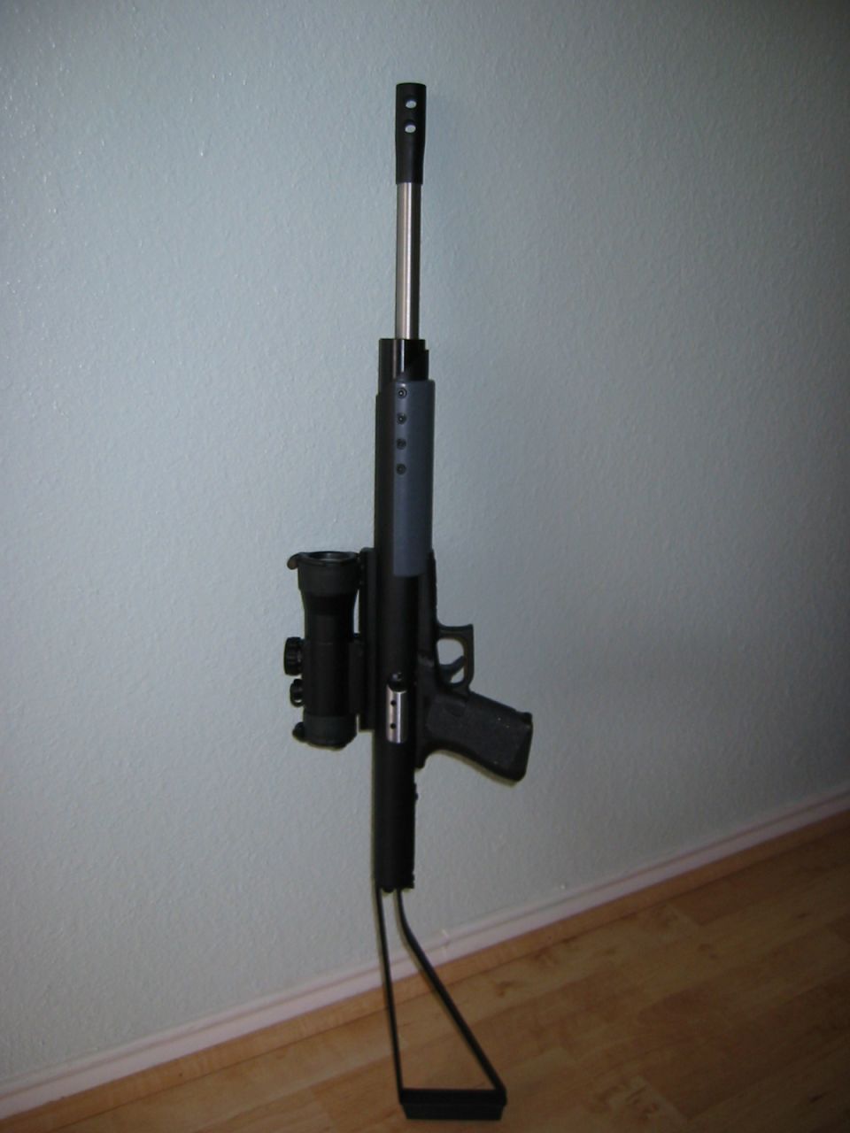 air rifle with scope mounted on it, leaning against a wall