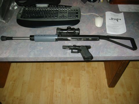 1996 Ford Bronco - A rifle with a scope and a handgun are laid out on a desk next to a manual.