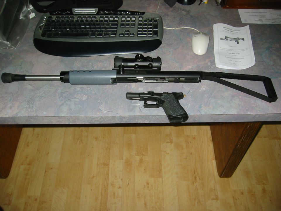 Rifle with scope and handgun on desk next to manual