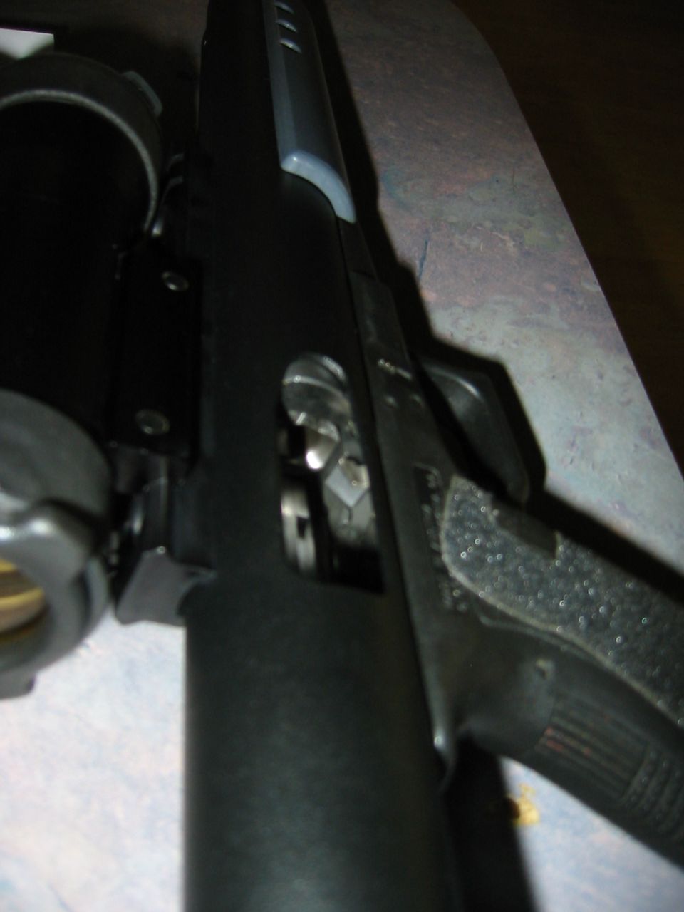 Close-up of gun mechanism with textured grip and scope mount