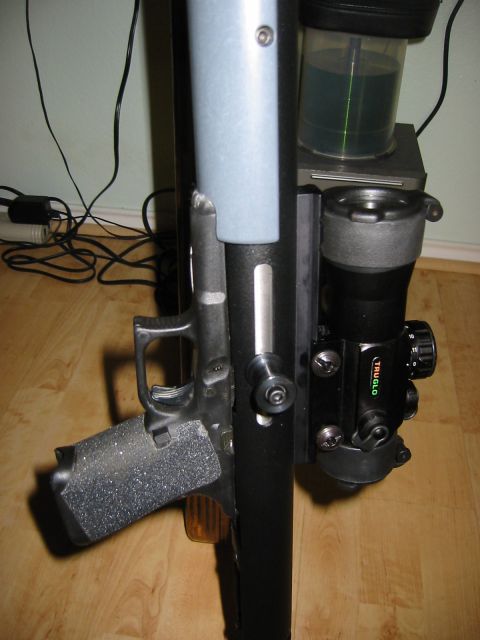 1996 Ford Bronco - A handgun with a TruGlo sight is mounted on a vertical support, with a container of green liquid above it.