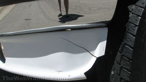 1996 Ford C-350 (Centurion Conversions) - Close-up of a damaged white bumper and a vehicle tire.