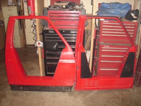 1989 Ford Bronco - Red vehicle doors are displayed in front of multiple red tool chests in a garage setting.