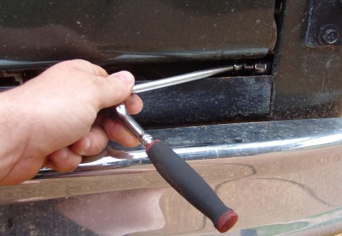 1975 Ford Bronco - Because of the body lift, the lower hinge bolt is above the bumper. But because of the filler, it's hard to get to.