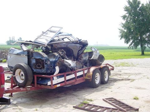 1992 Ford Bronco - A severely damaged SUV is transported on a trailer, its structure compromised by an impact.
