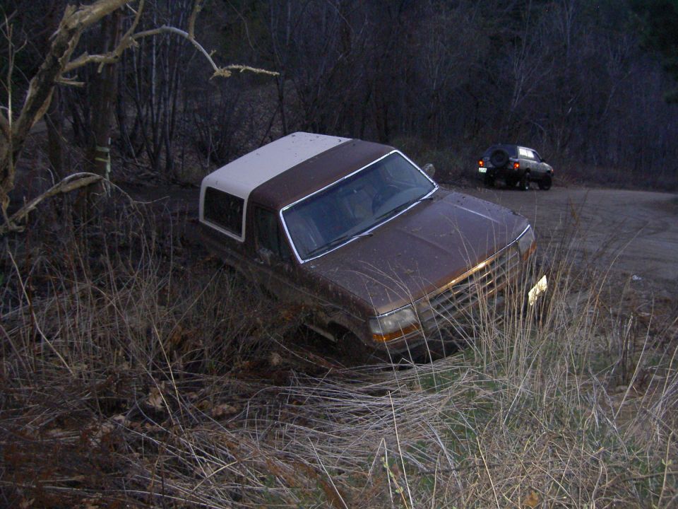 Brown 1992 Ford Bronco with a white top stuck in dry grass off-road