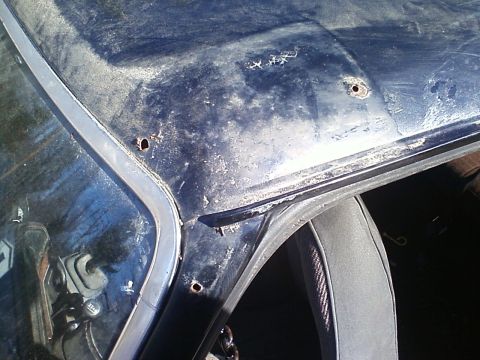 1990 Ford Bronco - Rust and holes are visible on the car's roof near the windshield.