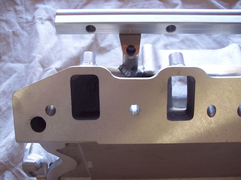 Close-up of an aluminum intake manifold with a fuel rail mounted above it