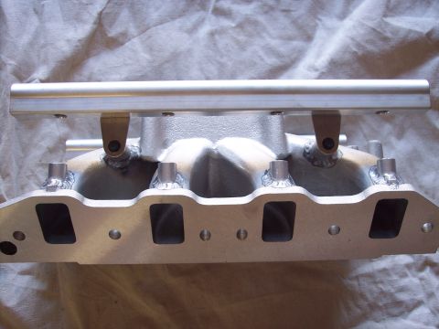1971 Ford Mustang - Close-up of an aluminum intake manifold with silver fuel rails, showing welded connections.
