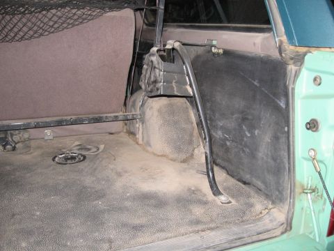 1996 Ford Bronco - The rear cargo area of the vehicle shows a worn rubber floor mat and a partially visible folded seat.
